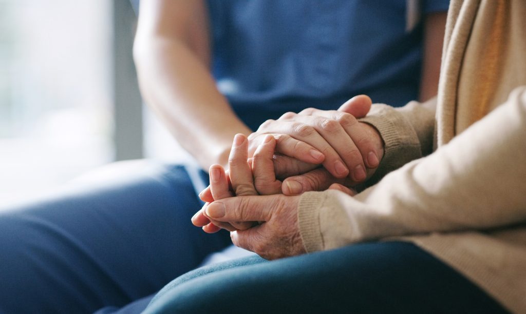 Cropped shot of a senior woman holding hands with a nurse